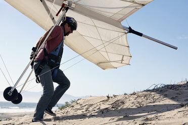 Man carrying hang glider on beach - ISF15898