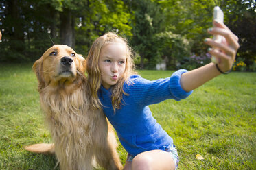 Girl taking selfie with pet dog in garden - ISF16028