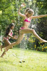Mädchen im Badeanzug springen über Garten-Sprinkler - ISF16035