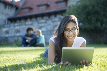 Junge Frau liegt im Gras und benutzt ein digitales Tablet - ISF16060