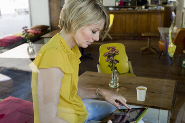 Mittlere erwachsene Frau benutzt digitales Tablet in einem Café - ISF16079