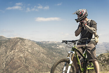 Downhill-Mountainbiker beim Aufsetzen des Helms - ISF16225