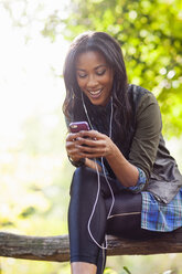 Young woman using smartphone on park bench - ISF16266