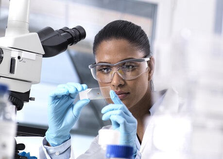 Female scientist examining a human sample on a microscope slide - ABRF00206