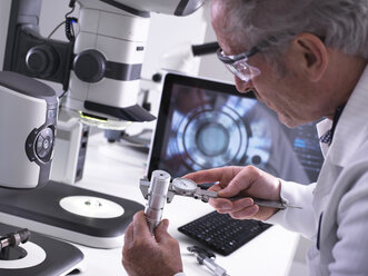 Engineer using a dial calliper and a 3d stereo microscope for quality control in the manufacturing of engineering components for industry - ABRF00214