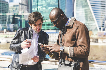 Russland, Moskau, zwei Geschäftsleute in der Stadt, die auf ein Mobiltelefon schauen - WPEF00601