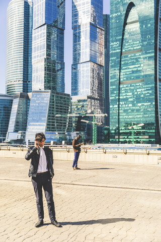 Russland, Moskau, zwei Geschäftsleute benutzen Handys in der Stadt, lizenzfreies Stockfoto