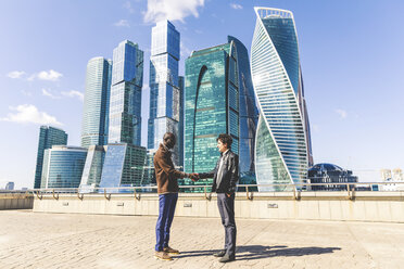 Russia, Moscow, two businessmen shaking hands in front of modern office buildings - WPEF00604