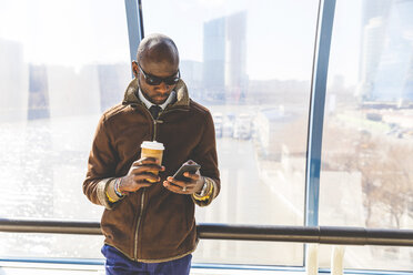 Businessman with coffee to go looking at smartphone - WPEF00609