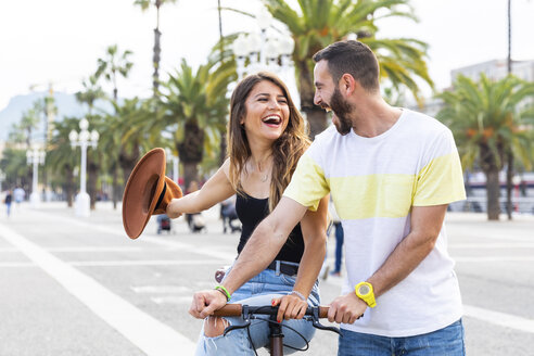 Spanien, Barcelona, Paar, das Spaß hat und gemeinsam auf einem Fahrrad an der Strandpromenade fährt - WPEF00619