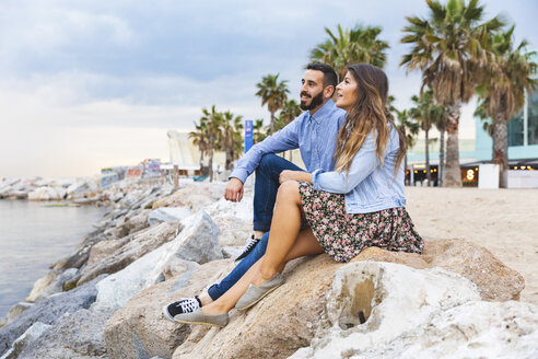 Spanien, Barcelona, Paar sitzt auf Felsen am Meer - WPEF00632