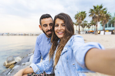 Spanien, Barcelona, lächelndes Paar, das ein Selfie am Meer macht - WPEF00634