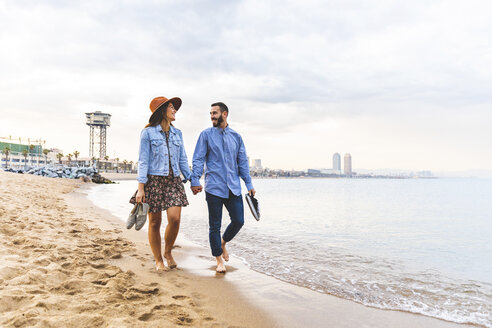 Spanien, Barcelona, Paar läuft barfuß am Strand - WPEF00636
