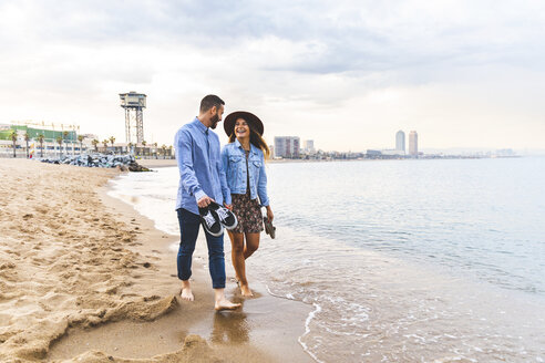 Spanien, Barcelona, Paar läuft barfuß am Strand - WPEF00637