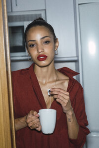 Porträt einer schönen jungen Frau mit einer Tasse Tee zu Hause - KKAF01125