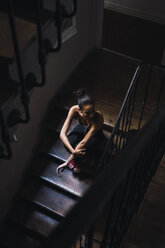 Beautiful young woman sitting in staircase in sunlight - KKAF01133