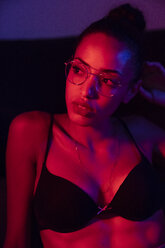 Porträt einer schönen jungen Frau mit BH und Brille bei künstlichem Licht - KKAF01139