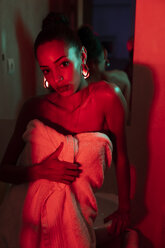 Portrait of beautiful young woman with towel in a dark illuminated room - KKAF01144