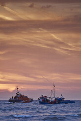 Lifeboat rescuing fishing boat at sunrise, Tenby, Wales, UK - ISF16305