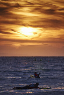 Zwei Personen beim Bodyboarding im Meer bei Sonnenaufgang, Tenby, Wales, UK - ISF16335