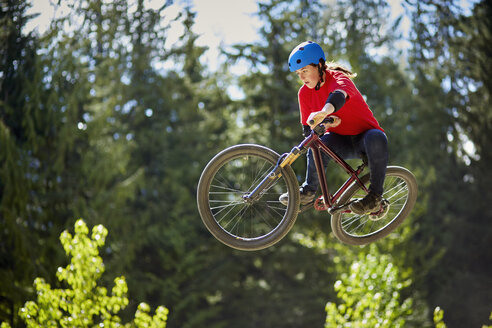 Junge Motorradfahrerin springt mitten in der Luft im Wald - ISF16341