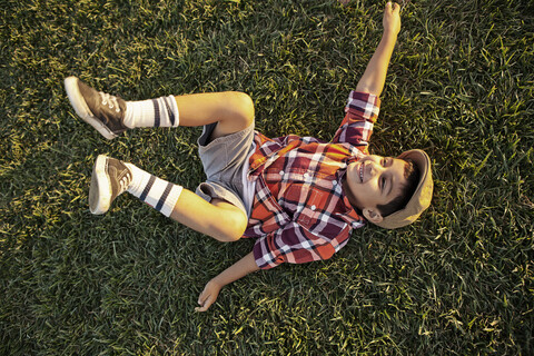 Junge liegt im Gras und spielt, lizenzfreies Stockfoto