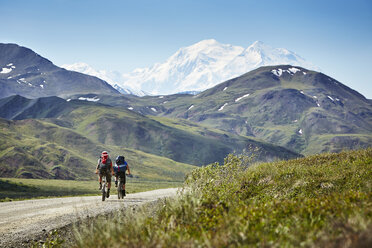 Mittleres erwachsenes Paar beim Radfahren auf einer Landstraße, Mount McKinley, Denali National Park, Alaska, USA - ISF16385