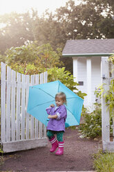 Weibliches Kleinkind, das im Garten spazieren geht und einen Regenschirm trägt - ISF16388