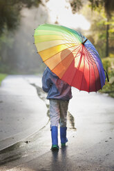 Rückansicht eines Jungen mit Regenschirm auf der Straße - ISF16393