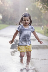Barfuß Mädchen läuft durch Pfützen auf regnerischen Straße - ISF16394