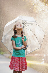 Girl holding up umbrella on rainy street - ISF16397