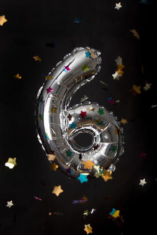 Silberne Ballon und Konfetti für 6. Geburtstag vor schwarzem Hintergrund, lizenzfreies Stockfoto