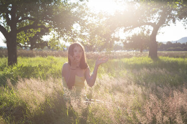 Young girl sitting on meadow at summer evening - LVF07216