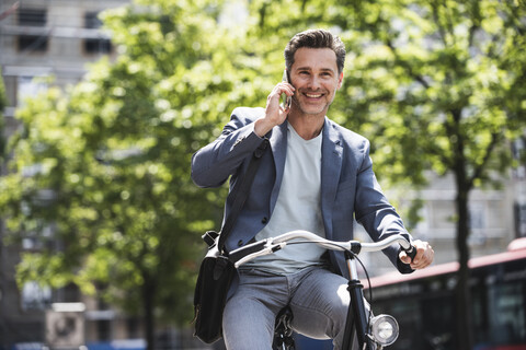 Smiling man on cell phone riding bike in the city stock photo