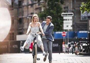 Happy carefree couple with bicycle in the city - UUF14423