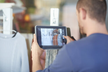 Mittlerer erwachsener Mann mit digitalem Tablet, der ein Schaufenster fotografiert - CUF39006