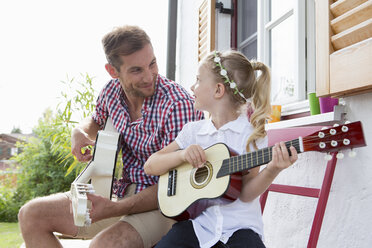 Girl playing guitar with father - CUF39024