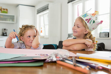 Two girls at table with paper and pencils - CUF39049