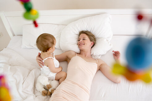Mother and baby daughter lying on bed, high angle - CUF39052