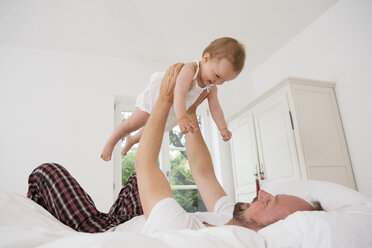 Father playing with baby daughter on bed - CUF39060