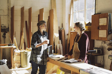 Two craftswomen drinking coffee in pipe organ workshop - CUF39080