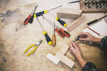 Hände einer jungen Handwerkerin, die ein Bauteil in einer Orgelpfeifenwerkstatt hält - CUF39084