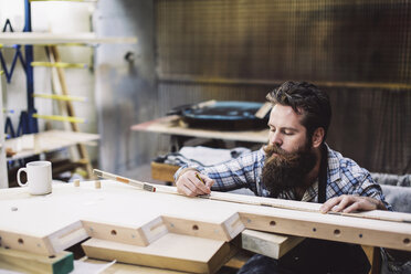 Cropped shot of mid adult craftsman measuring wood component in organ workshop - CUF39092