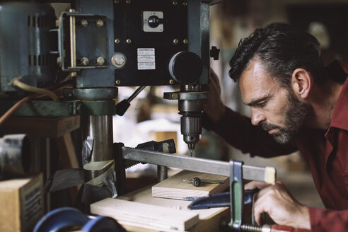 Älterer Handwerker beim Bohren von Bauteilen in der Orgelwerkstatt - CUF39097