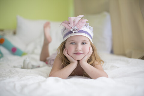 Portrait of young girl in princess headdress on bed stock photo