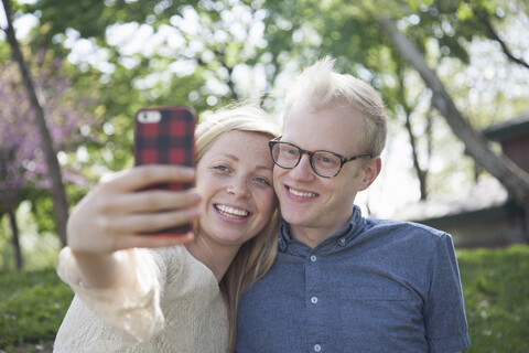 Junges Paar im Park macht Selfie mit Smartphone, lizenzfreies Stockfoto
