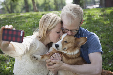 Junges Paar im Park macht Selfie und küsst Corgi-Hund - ISF16487