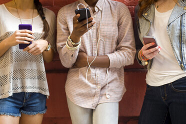 Mid section of three young women using mobile phones - ISF16514