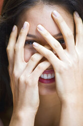 Portrait of young woman with hands covering face - ISF16517