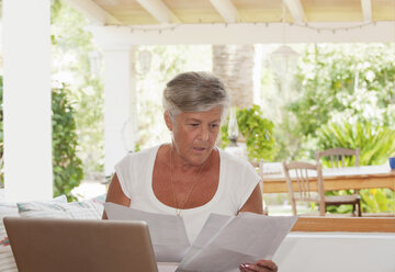 Ältere Frau bezahlt Rechnungen auf Laptop - CUF39180